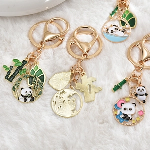 Detail view of cute panda and bamboo enamel keychains on white faux fur background