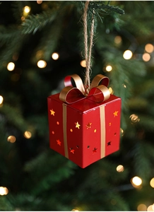 Détail d'un ornement de boîte cadeau rouge en métal avec nœud doré et étoiles lumineuses