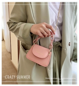 Detail of pink jelly crossbody bag with chunky chain handle and gold shoulder strap on model