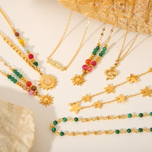 Flat lay of 18K gold plated necklaces featuring MOM, sun, and star charms with colorful beads
