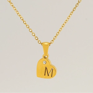 Détail du collier avec pendentif cœur doré gravé de la lettre M et orné d'un zircon