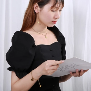Model wearing a gold fan-shaped necklace, earrings, and bracelet jewelry set