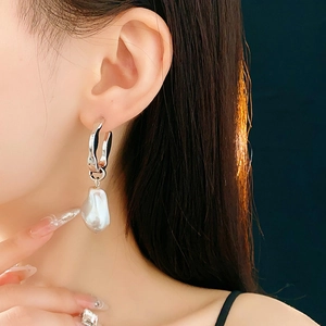 Boucles d'oreilles élégantes en perles baroques portées par un mannequin sur fond sombre