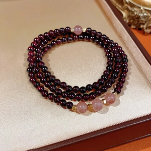 Macro detail of multi-layer garnet and strawberry quartz bracelet with gold accents