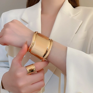 Macro shot showing the high-polished mirror finish on wide golden metal cuff bracelet