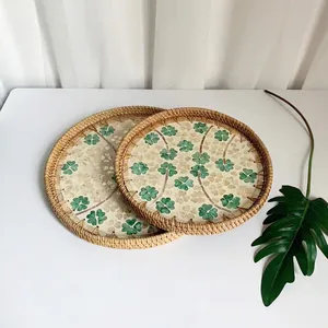 Detailed view of two handmade rattan trays with inlaid green four-leaf clover shell designs