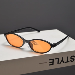 Detail of vintage oval black sunglasses with vibrant orange lenses on a book prop