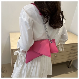 Detail view of pink irregular geometric chain bag on a model in a minimalist setting
