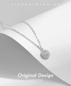 Close-up of S925 silver halo necklace with sparkling cubic zirconia on white surface