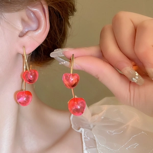 Close-up of a model wearing sweet pink resin cherry earrings with gold-toned metal stems