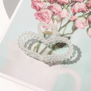 Detail of heart-shaped hair claw with iridescent pearls and golden metal spring