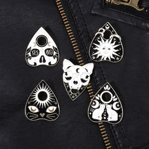 Set of 5 black and white Gothic enamel pins with cat skull and sun designs on a jacket