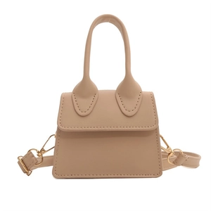 Detail einer beigen Mini-Handtasche aus Kunstleder mit goldenen Metallbeschlägen und Gurt