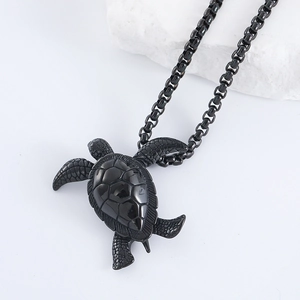 Detailed close-up of a black turtle pendant on a decorative white coral stone stand