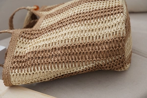 Close-up of striped straw tote bag showing natural weave texture and wood bead detail