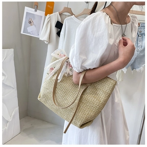 Detail of summer straw tote bag with delicate weaving, lace bow and pink floral embroidery
