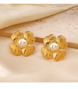 Detail of 18K gold plated flower stud earrings with pearl center on stone background