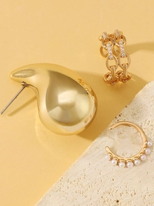 Detail of elegant gold drop earrings, zircon chain clip and pearl ear cuff jewelry set