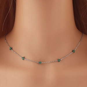 Detail view of silver O-chain necklace with five green clover pendants on neck