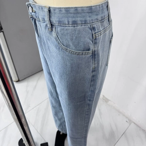 Detailansicht der hellblauen Jeans mit Metallknopfleiste und feinen Nähten im Nahaufnahme