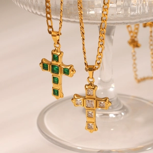 Macro view of gold Figaro necklaces with zircon-studded cross pendants in green and white