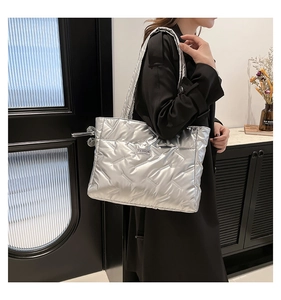 Silver padded tote bag featuring geometric quilted patterns worn by a model in a casual setting