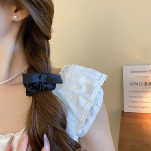 Close-up of black satin bow hair tie with silk texture worn on model's ponytail