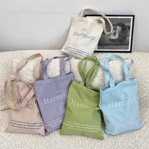 Close-up of colorful canvas tote bags in five pastel shades with printed text