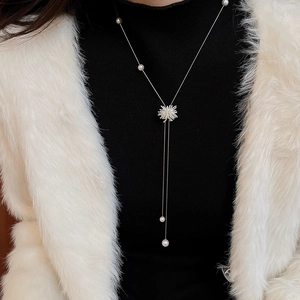 Collier à franges argenté avec perles blanches et pendentif flocon sur pull noir