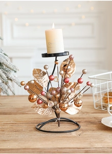 Detail of Christmas iron candle holder with golden leaves and festive berry ornaments