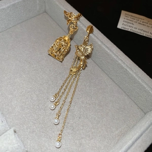 Detailansicht asymmetrischer Vogelohrringe mit Perlen und Quasten in einer Schmuckbox
