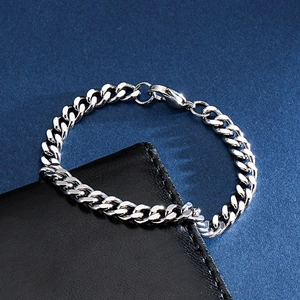 Close-up of polished silver Cuban link bracelet with lobster clasp on leather wallet