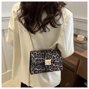 Modische Handtasche mit Leopardenmuster und goldener Kette auf der Schulter getragen