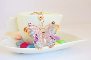 Close-up of golden butterfly keychain with colorful rhinestones and purple gemstones
