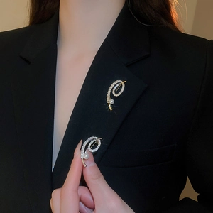 Détail de broches en perles et zircons plaqués or sur un blazer noir élégant pour femme