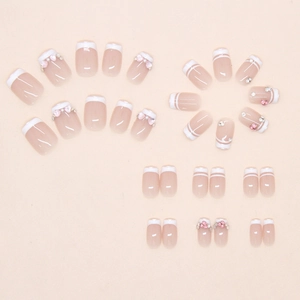 Detail view of nude pink french tip press-on nails with 3D hearts and pearls