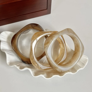 Detailed view of three resin bracelets in brown and cream marble textures on a shell tray