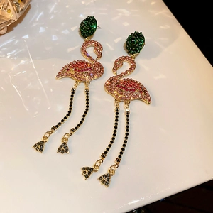 Macro shot of flamingo earrings featuring pink rhinestones and black tassel chain detail