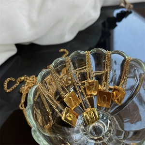 Macro shot of gold-plated titanium steel chain and square initial pendant in glass bowl