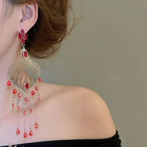 Close-up of vintage palace style silver earrings with red crystal drop tassels on a model