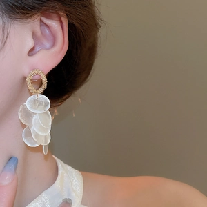 Detailed close-up of gold hoop earrings featuring layered white shell fringe on a model