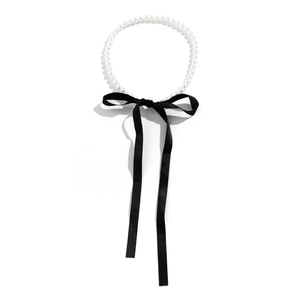 Elegant vintage pearl necklace featuring a black ribbon bow tie on a white background