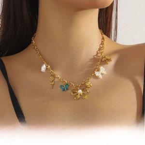 Close-up of gold chain necklace featuring blue butterfly and pearl bow charms on a model