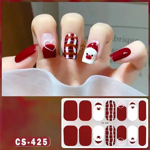 Detailed macro view of Christmas nail stickers featuring Santa and red plaid patterns