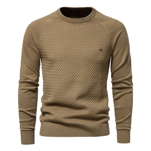 Detailed view of dark camel knit sweater with textured diamond pattern and ribbed crew neck