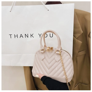 Detail of cream jelly shell bag with V-shaped texture and golden chain strap
