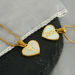 Gold snake chain necklace with heart shell pendant featuring letter H and T