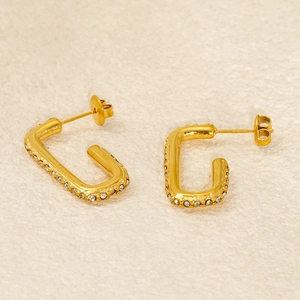 Elegant gold rectangular earrings with diamond accents on a textured fabric background