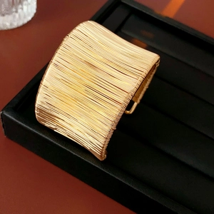 Macro di bracciale a fascia larga dorato con fili intrecciati su supporto in pelle