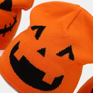 Close-up of orange knitted Halloween pumpkin beanie with black Jack-o'-lantern face detail